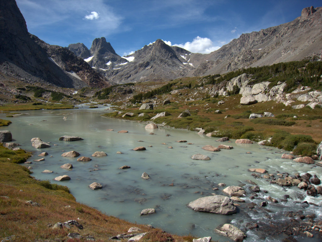 The milky, glacier-fed waters of the North Fork of Bull Lake Creek. Blaurock Pass is the snow-free low spot on the ridge with the cloud immediately above it. The aptly named Turret Peak is the most prominent on the skyline.