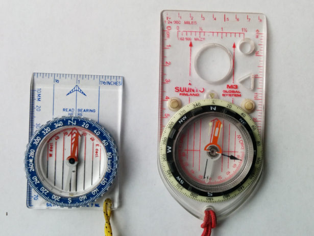 A non-adjustable (left) and adjustable compass (right), both pointing towards True North. With the non-adjustable compass, the needle is positioned to the right/east of the orienting arrow ("the shed"), whereas with the adjustable compass the needle is positioned directly over it.